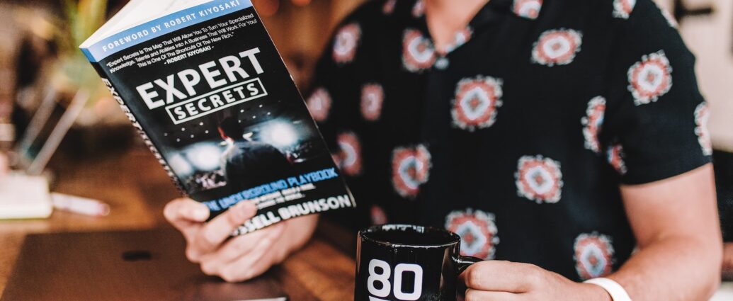 smiling man reading book while holding mug