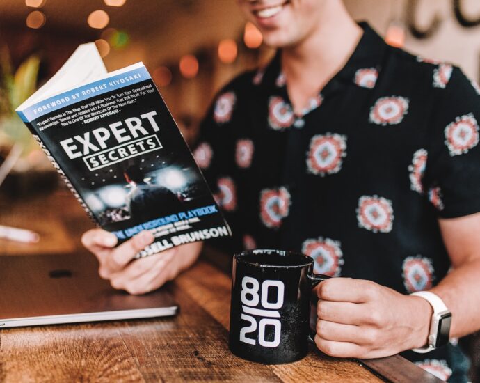 smiling man reading book while holding mug