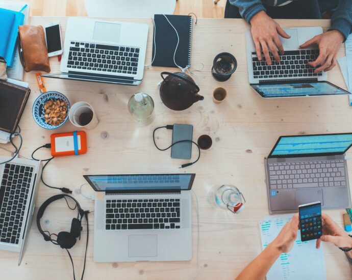 people sitting down near table with assorted laptop computers